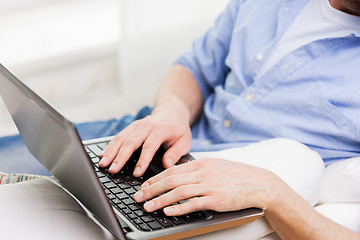 Image showing close up of man typing on laptop computer at home