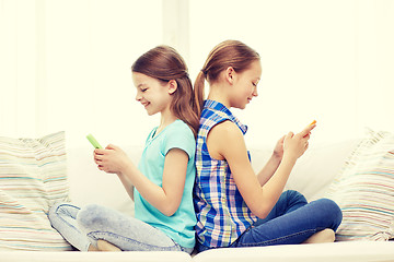 Image showing happy girls with smartphones sitting on sofa