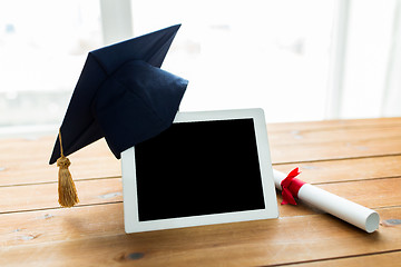Image showing close up of tablet pc with mortarboard and diploma
