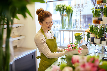 Image showing smiling florist woman making bunch at flower shop