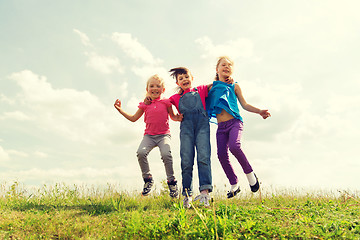 Image showing group of happy kids jumping high on green field