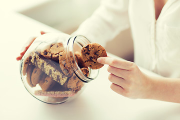 Image showing close up of hands with chocolate cookies in jar