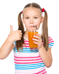 Image showing Little girl is drinking carrot juice