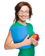 Image showing Young student girl is holding book and apple