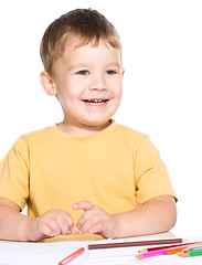 Image showing Little boy is drawing using color pencils