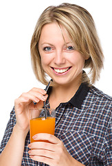 Image showing Young woman is drinking carrot juice