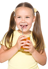 Image showing Little girl is drinking carrot juice