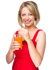 Image showing Young woman is drinking carrot juice