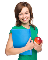 Image showing Young student girl is holding book and apple