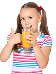 Image showing Little girl is drinking orange juice