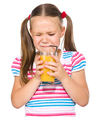 Image showing Little girl unwillingly drinking orange juice