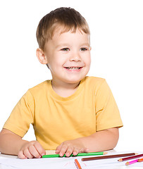 Image showing Little boy is drawing using color pencils