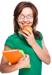 Image showing Young student girl is holding book and apple