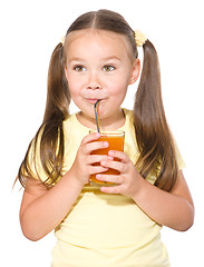 Image showing Little girl is drinking carrot juice