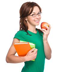 Image showing Young student girl is holding book and apple