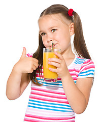 Image showing Little girl is drinking orange juice