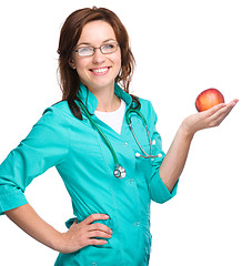 Image showing Young lady doctor is holding a red apple