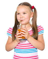 Image showing Little girl is drinking carrot juice