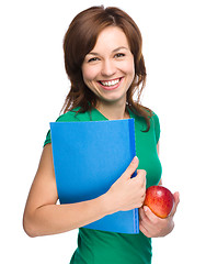 Image showing Young student girl is holding book and apple