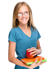 Image showing Young student girl is holding book and apple
