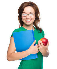 Image showing Young student girl is holding book and apple