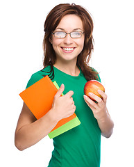 Image showing Young student girl is holding book and apple