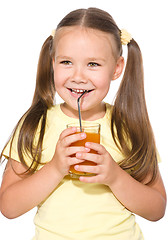 Image showing Little girl is drinking carrot juice