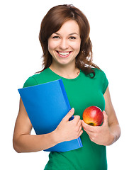 Image showing Young student girl is holding book and apple