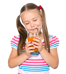 Image showing Little girl is drinking carrot juice