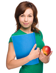 Image showing Young student girl is holding book and apple