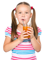 Image showing Little girl is drinking carrot juice