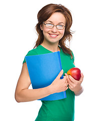 Image showing Young student girl is holding book and apple