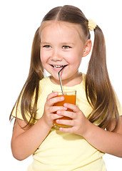 Image showing Little girl is drinking carrot juice