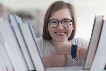 Image showing portrait of famale student selecting book to read in library