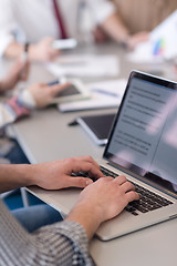 Image showing close up of business man hands typing on laptop with team on mee