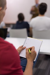 Image showing male student taking notes in classroom