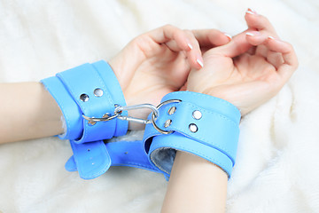 Image showing female hands in leather handcuffs. eagerly grabbed the sheets.. sex toys.