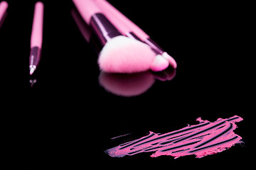Image showing lipstick with a brush make-up on black 