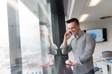 Image showing young business man speaking on  smart phone at office