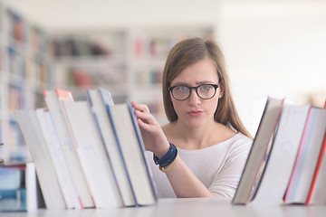 Image showing portrait of famale student selecting book to read in library