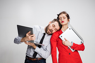 Image showing The young businessman and businesswoman with laptops on gray background