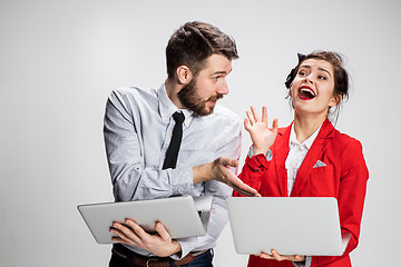 Image showing The young businessman and businesswoman with laptops communicating on gray background