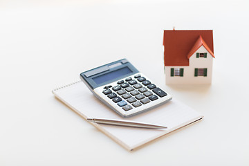 Image showing close up of home model, calculator and notebook