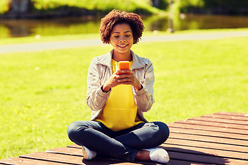 Image showing happy african young woman messaging on smartphone