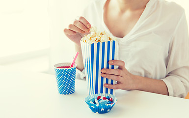 Image showing woman eating popcorn with drink and candies