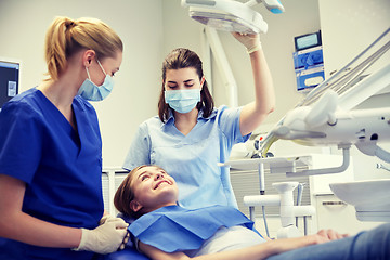 Image showing happy female dentist with patient girl at clinic