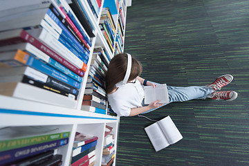 Image showing female student study in library, using tablet and searching for 