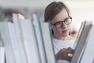 Image showing portrait of famale student selecting book to read in library