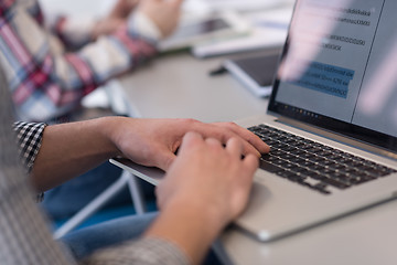 Image showing close up of business man hands typing on laptop with team on mee