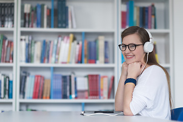 Image showing female student study in library, using tablet and searching for 